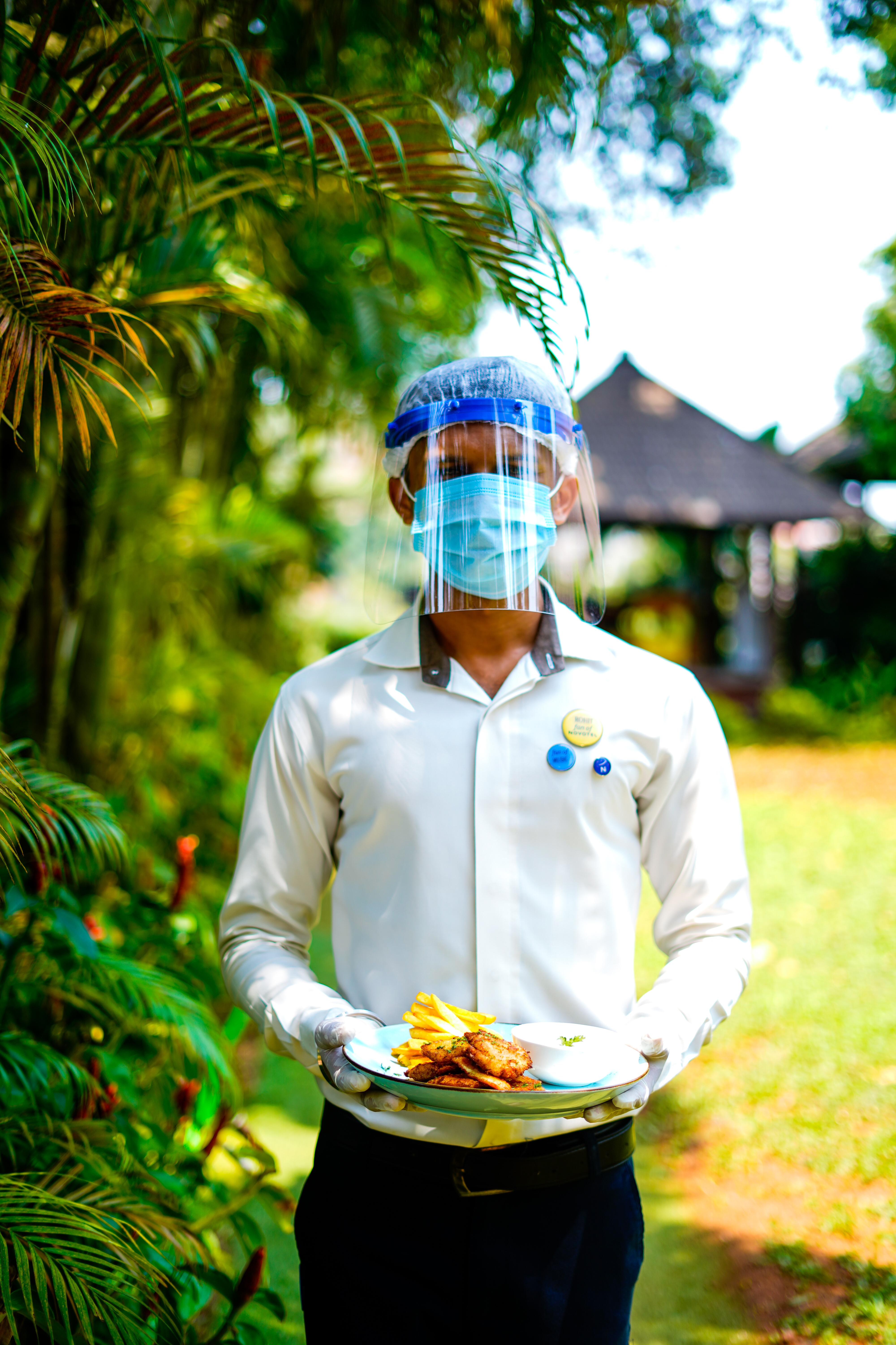 Novotel Goa Resort & Spa Candolim Exterior foto A hotel employee wearing a face shield and a face mask